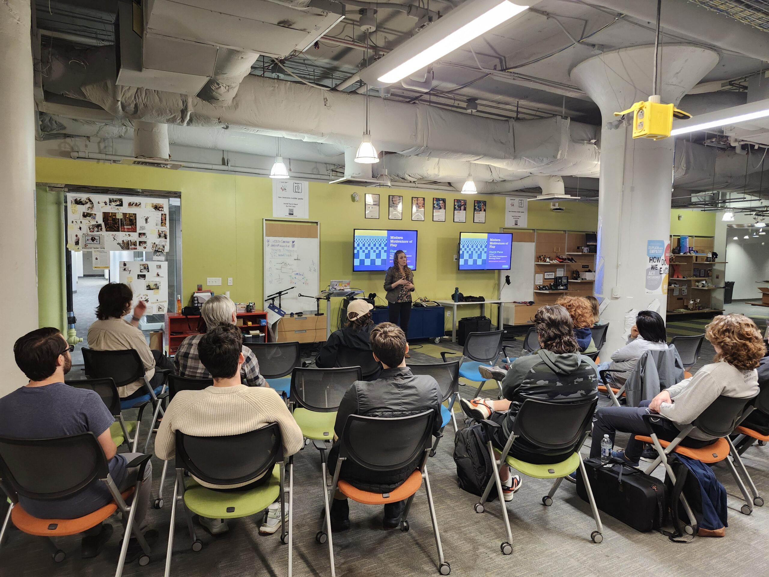 Author Cheryl Platz stands in front of a slide from her book The Game Development Strategy Guide while giving a guest lecture at Drexel University's Entrepreneurial Game Studio on November 5, 2025. A number of students and instructors are seen in the foreground.